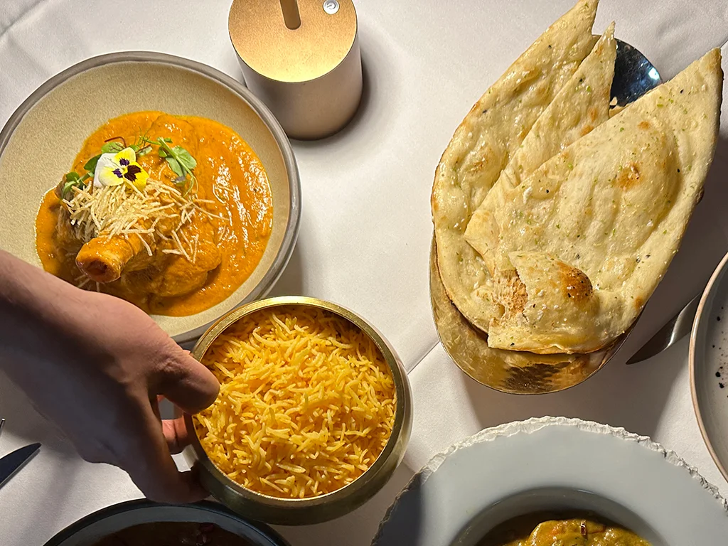 hand holding dish of Saffron rice , Naan bread on another dish, The Oven