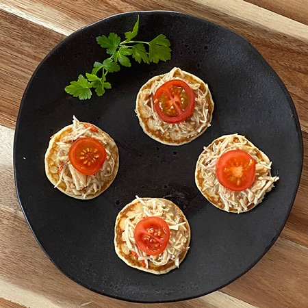 small blinis with crab meat over them, tomato on top and on a black dish. eating well