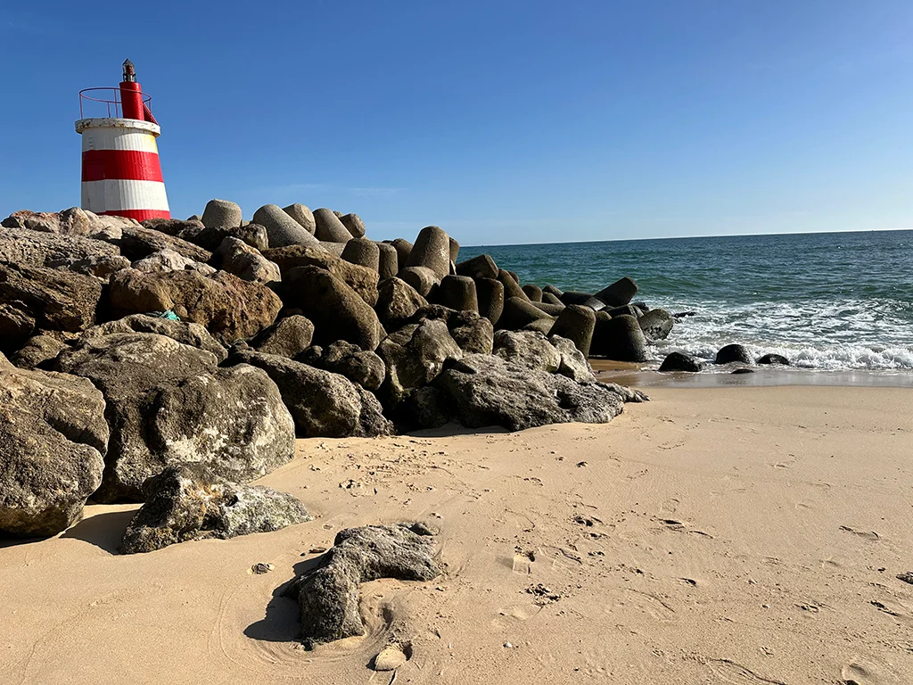Beach scene, rocks on the left side. small light for ships