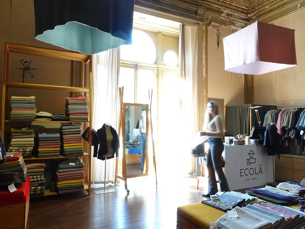 interior of Ecola, Lisbon, Portugal, wool products on shelves, woman in background