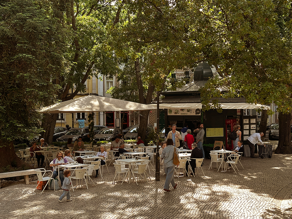 Plaza with shady trees, Kiosk Campo de Ourique, shadows in the forefront, where to sit in Lisbon