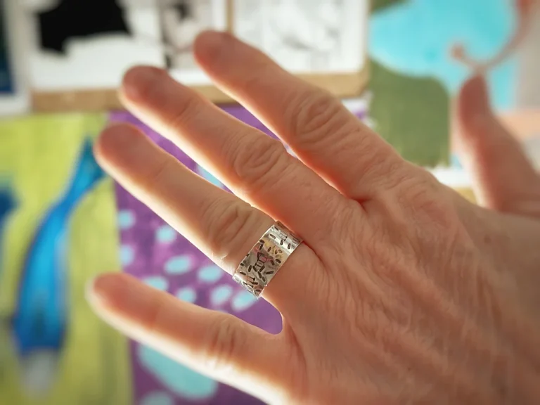 hand, in front of paintings, one silver ring, Edit Ring, Birthday ring